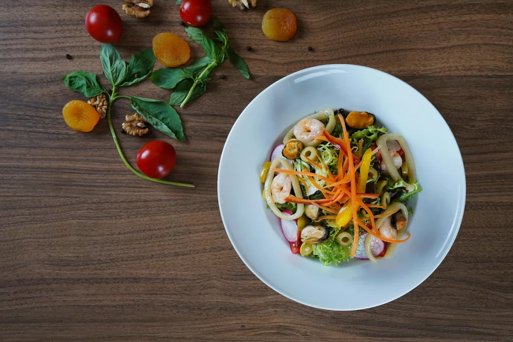 Salade composée avec crevettes, pâtes, légumes croquants et herbes fraîches