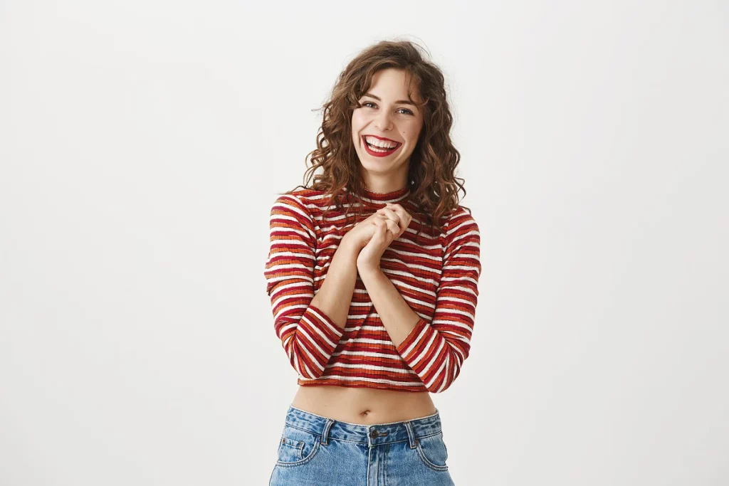 Jeune femme souriante en t-shirt rayé rouge et jean sur fond blanc