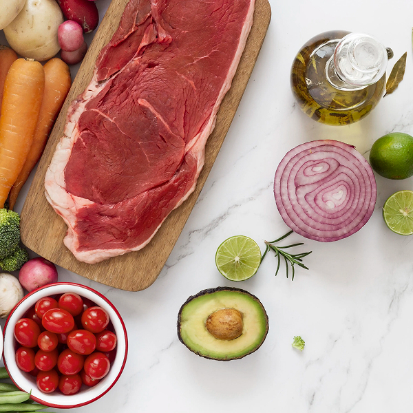 Pièce de bœuf crue avec légumes frais, avocat, citron vert et huile d’olive
