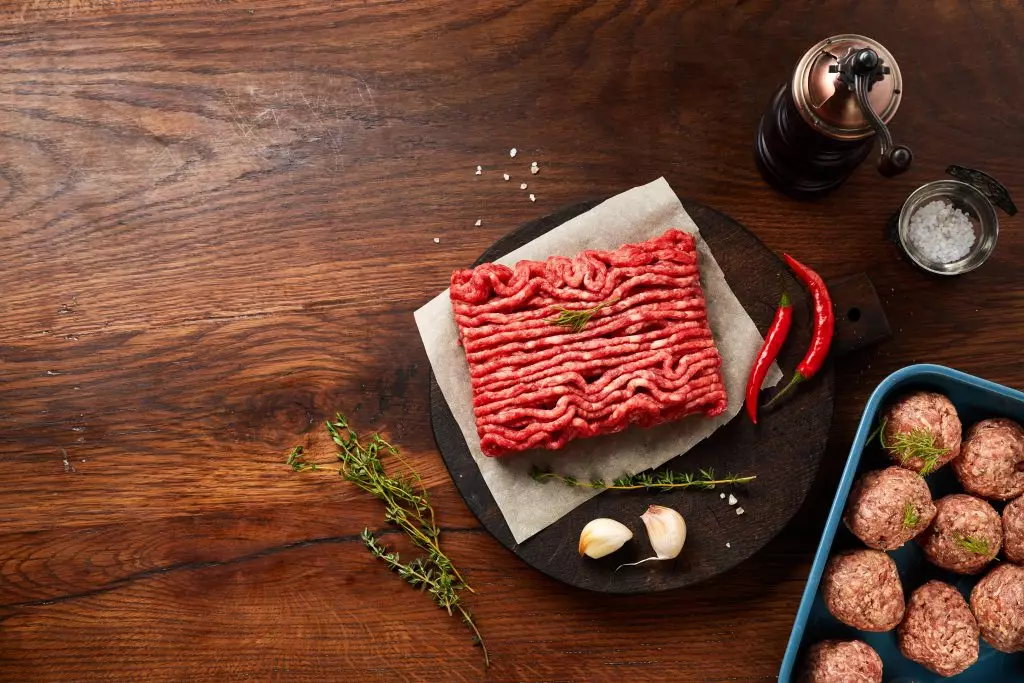 Viande hachée de bœuf crue avec herbes, ail et piments sur planche