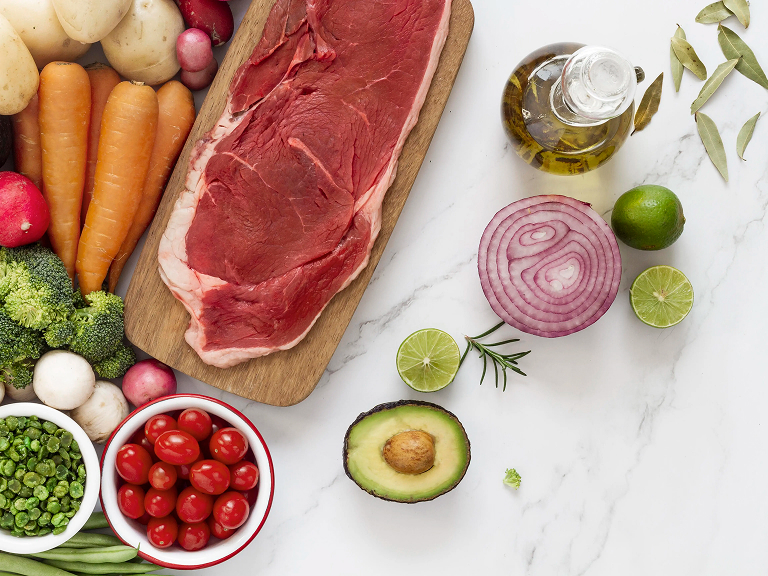 Pièce de bœuf crue avec légumes frais, avocat, citron vert et huile d’olive