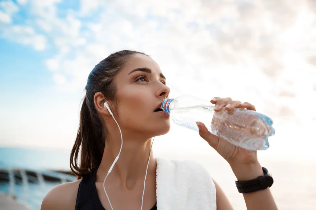 Femme sportive buvant de l’eau après un entraînement en extérieur