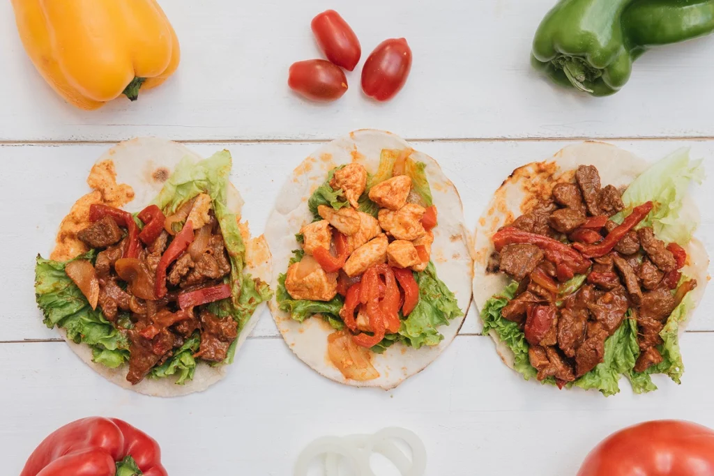 Trois tacos garnis de bœuf et poulet avec légumes et poivrons.